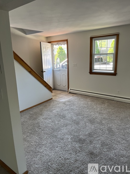 A room with a carpeted floor, a window, and a door leading to a balcony.