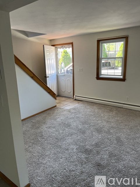 A room with a carpeted floor, a window, and a door leading to a balcony.