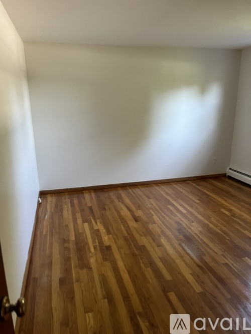 A room with wooden flooring and white walls.