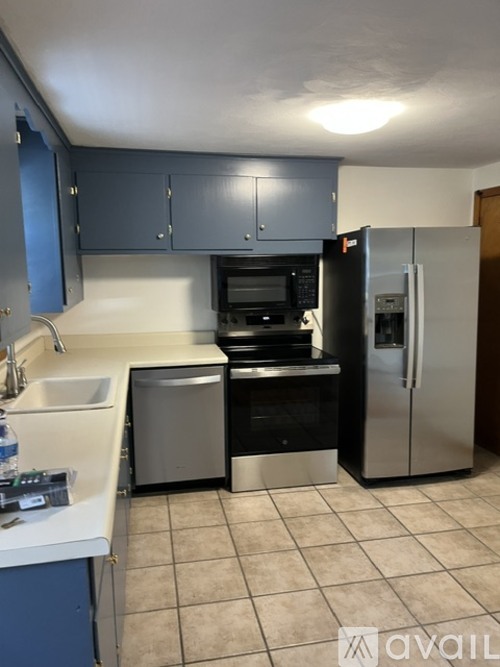 A kitchen with blue cabinets and a white fridge.