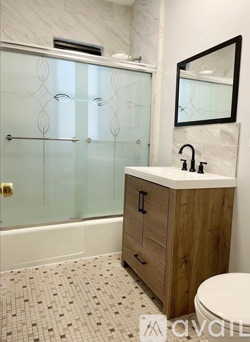 A bathroom with a glass shower door, a wooden cabinet, and a white toilet.