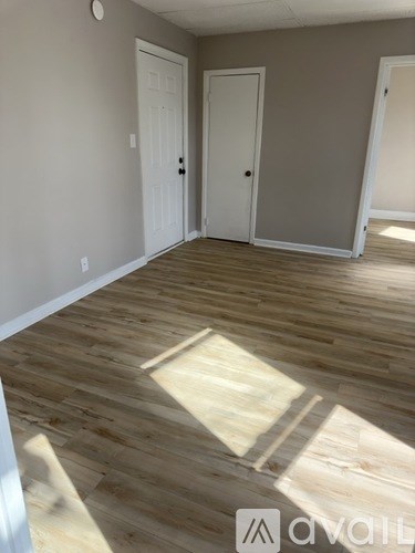 A room with wooden floors and two white doors.