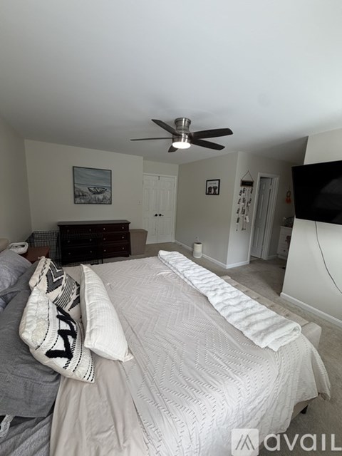 A bedroom with a large bed and a ceiling fan.
