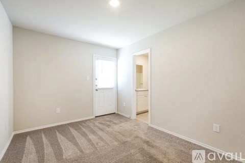 A room with a carpeted floor and two doors.