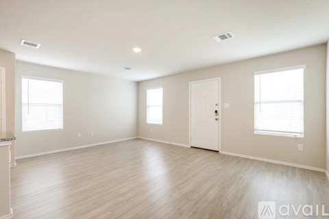 A spacious room with wooden flooring and white walls.