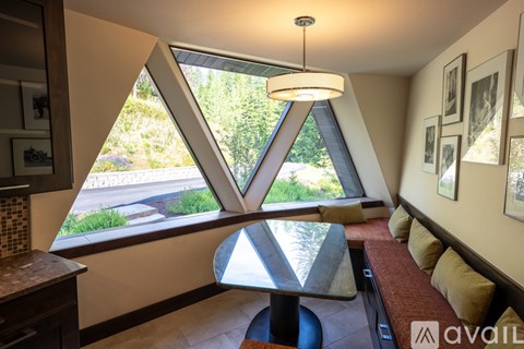 A modern dining area with a glass table and a view of the garden outside.