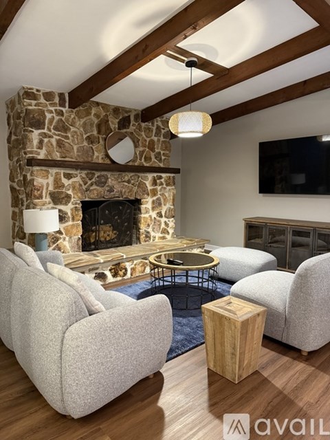 A living room with a stone fireplace and a wooden coffee table.