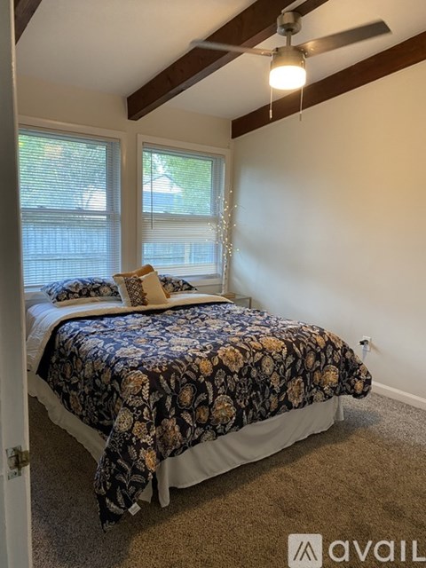 A bedroom with a bed covered in a floral print bedspread.