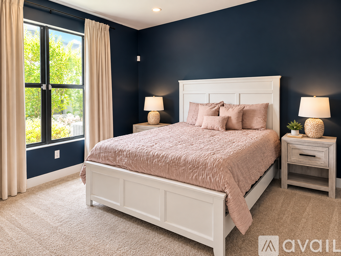 A bedroom with a large bed and two lamps.