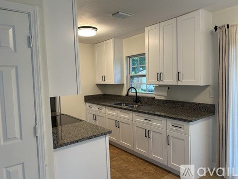 A kitchen with white cabinets and granite countertops.