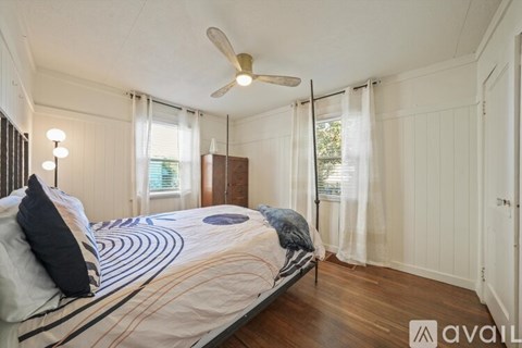 A bedroom with a bed, a ceiling fan, and a window with curtains.
