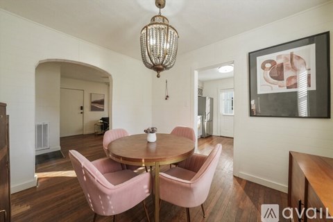 A dining room with a round table and pink chairs.