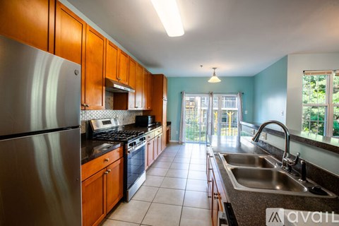 A kitchen with a stainless steel refrigerator and wooden cabinets.
