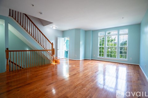 A spacious room with wooden floors and a staircase.