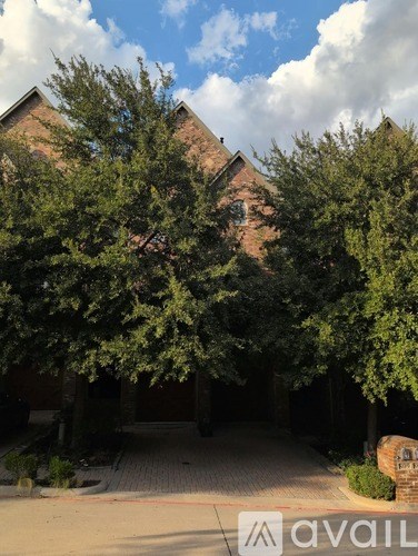 A tree in front of a building with a brick wall.