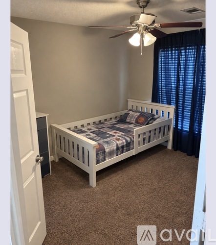 A bedroom with a bed, carpet, and a ceiling fan.