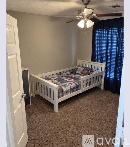 A bedroom with a bed, carpet, and a ceiling fan.