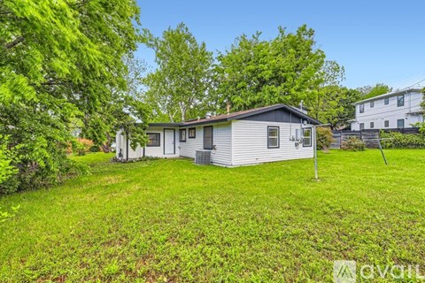 A house with a green lawn and trees in the background.