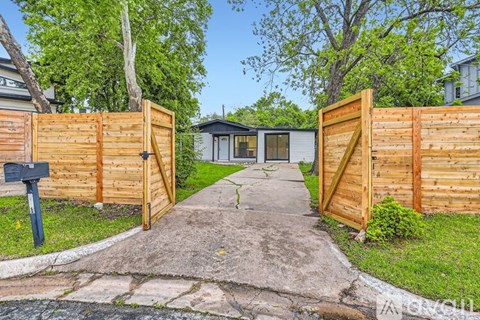 A wooden gate blocks the entrance to a driveway.