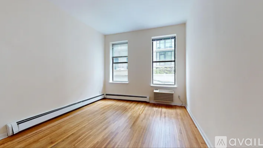 A room with wooden floors and two windows.