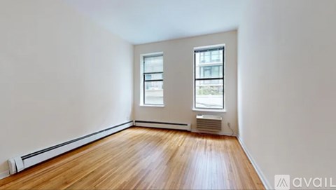 A room with wooden floors and two windows.