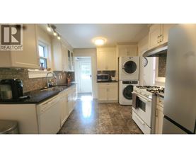 A kitchen with a washing machine and a fridge.