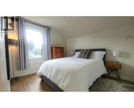 A bedroom with a large bed and a window with curtains.