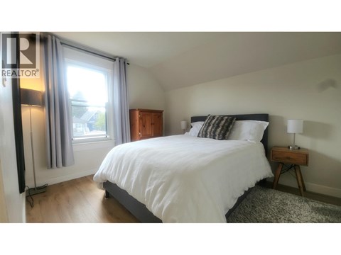 A bedroom with a large bed and a window with curtains.