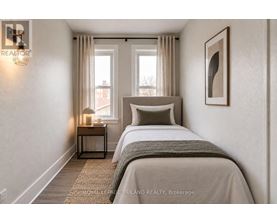 A bedroom with a large bed and a nightstand with a lamp.