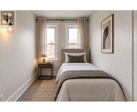A bedroom with a large bed and a nightstand with a lamp.