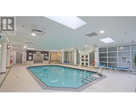 A large indoor swimming pool with a tiled floor and a glass wall on the right side.