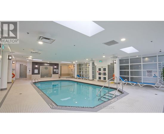 A large indoor swimming pool with a tiled floor and a glass wall on the right side.