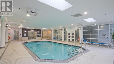 A large indoor swimming pool with a tiled floor and a glass wall on the right side.