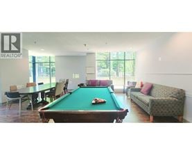 A pool table is in the middle of a room with a couch and a dining table.