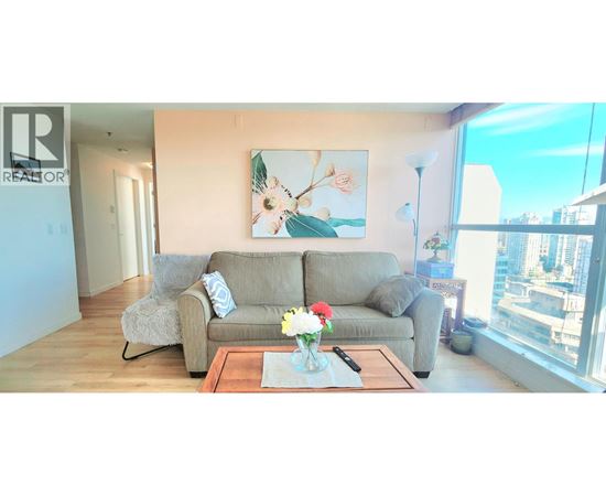 A living room with a grey couch, a coffee table, and a painting on the wall.