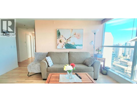 A living room with a grey couch, a coffee table, and a painting on the wall.