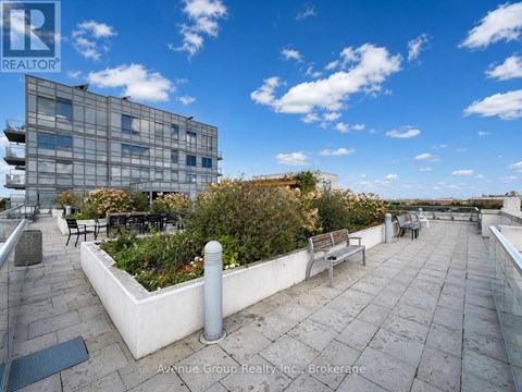 A rooftop patio with benches and a building in the background.