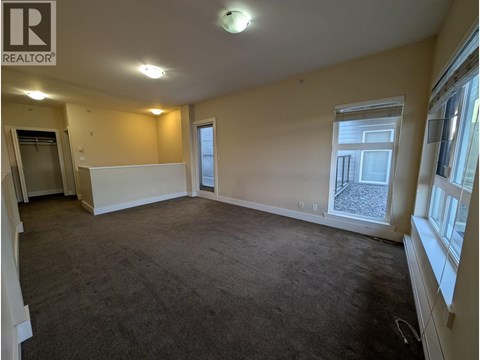 A spacious room with a carpeted floor and a window overlooking a construction site.
