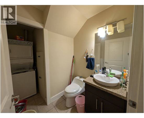 A bathroom with a toilet, sink, and a cabinet with a mirror above it.
