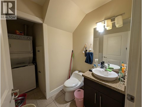 A bathroom with a toilet, sink, and a cabinet with a mirror above it.