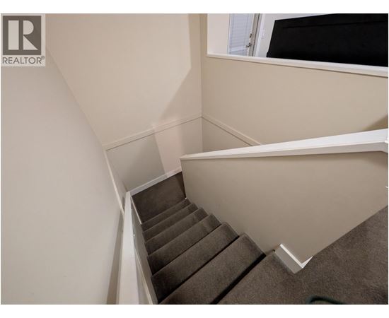 A staircase with a carpeted runner and white risers.