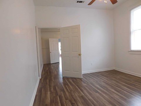A room with a white door and wooden flooring.
