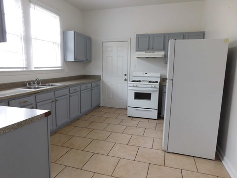 A kitchen with a refrigerator, sink, and cabinets.