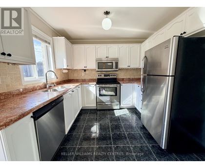 A kitchen with a black fridge and white cabinets.