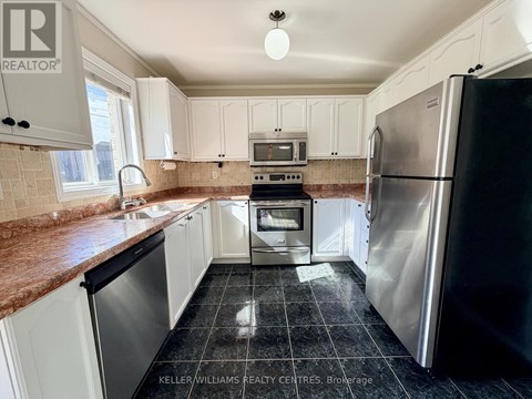 A kitchen with a black fridge and white cabinets.