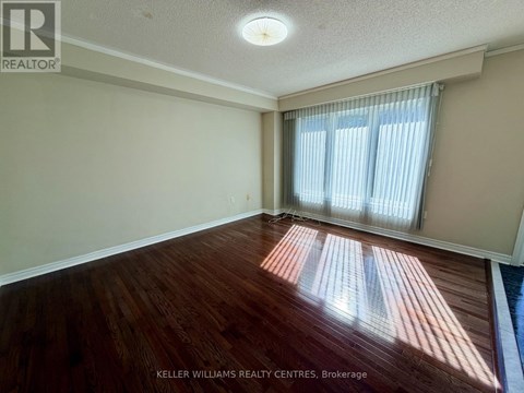 A room with wooden flooring and a window with curtains.