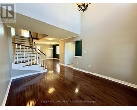 A spacious room with wooden floors and a staircase leading to the upper level.