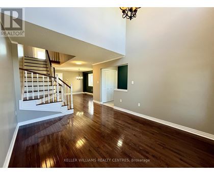 A spacious room with wooden floors and a staircase leading to the upper level.