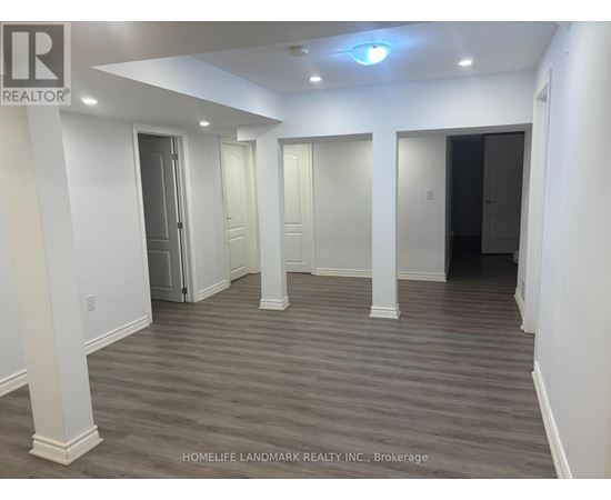 A spacious room with wooden flooring and white walls.
