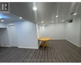 A room with a wooden table and grey carpet.